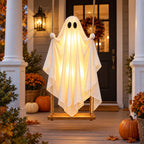 Festwick GlowSwing ghost swing glowing warm white on a front porch at dusk beside pumpkins