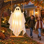 Kids walking past a glowing ghost swing hanging from a tree at dusk